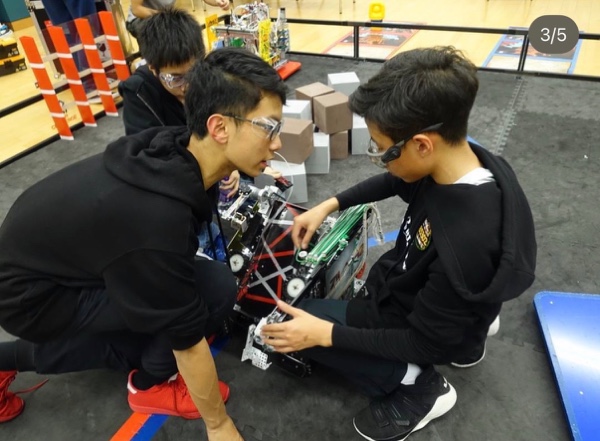 Team members adjusting a robot beside the competition field